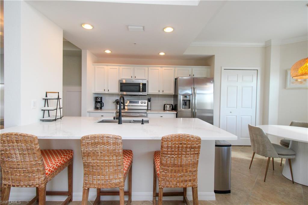 9554 Trevi Court, Unit 4737 Naples, FL 34113 - Photo 23 of 49 a kitchen with stainless steel appliances granite countertop a stove top oven a sink a dining table and chairs