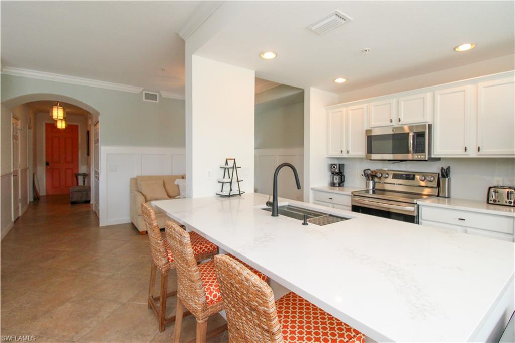 9554 Trevi Court, Unit 4737 Naples, FL 34113 - Photo 25 of 49 a kitchen with stainless steel appliances a stove a sink a microwave a refrigerator and cabinets