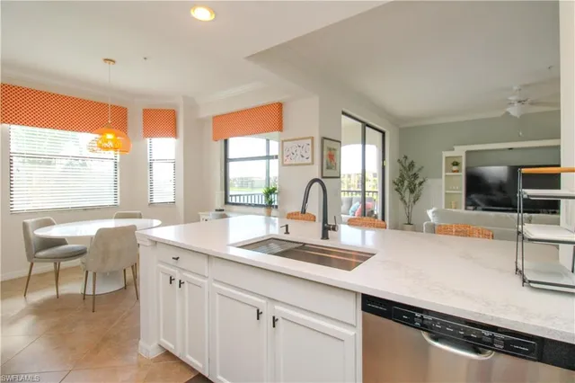 a living room with stainless steel appliances furniture a chandelier and a kitchen view