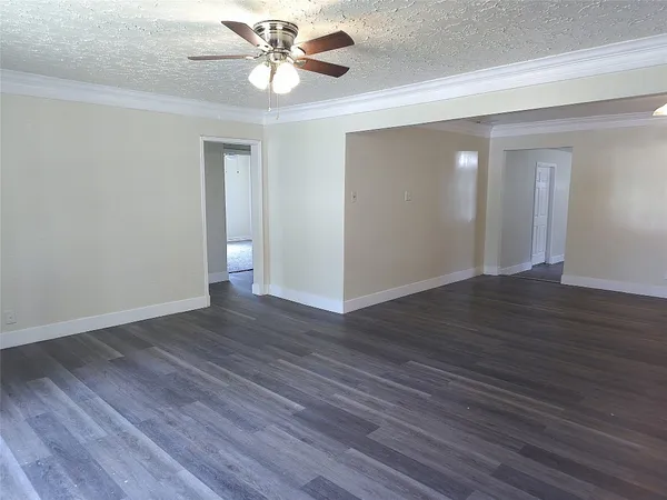 a view of an empty room with wooden floor and a ceiling fan