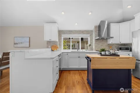 a kitchen with a sink a stove a refrigerator and white cabinets