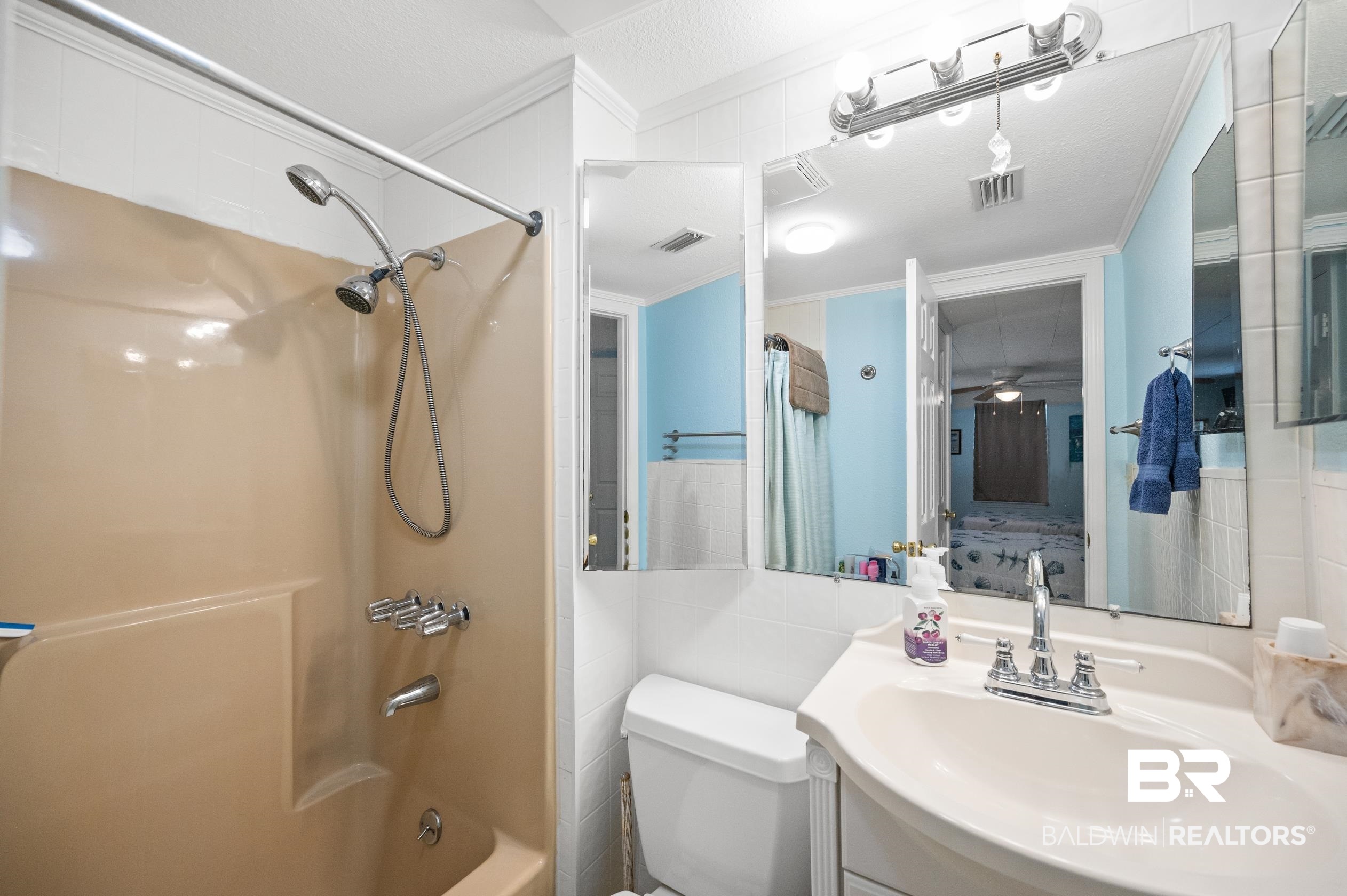 5392 Ornacor Avenue Orange Beach, AL 36561 - Photo 22 of 48 Full bathroom with vanity, shower / bathtub combination with curtain, a textured ceiling, tile walls, and toilet