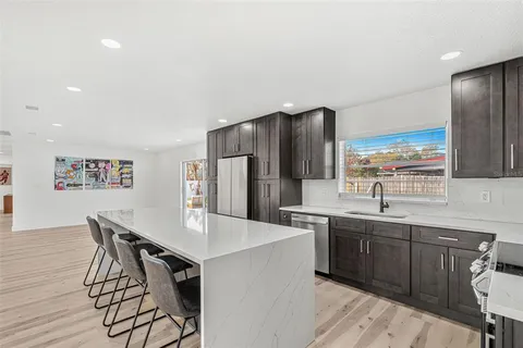 a kitchen with stainless steel appliances a sink a stove a refrigerator cabinets and dining table