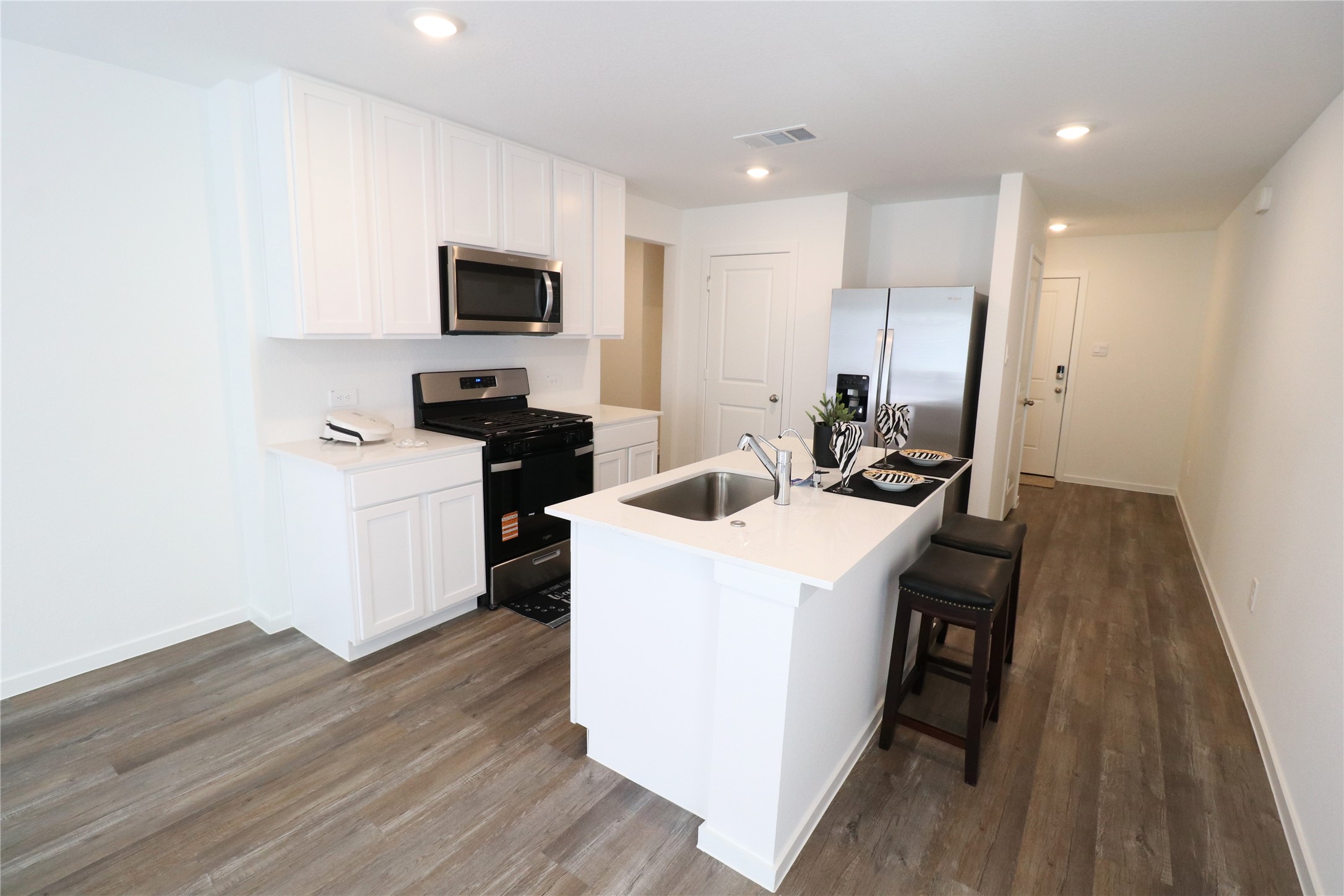 24134 Chirp Street Splendora, TX 77372 - Photo 7 of 14 a kitchen with a sink a microwave a stove and refrigerator