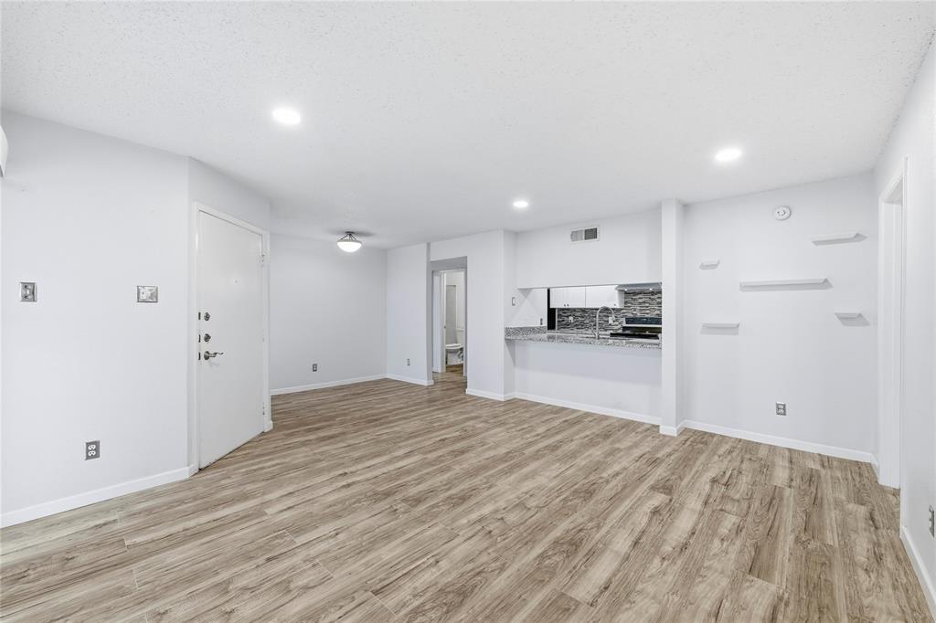 a view of a kitchen with kitchen island wooden floor appliances and cabinets