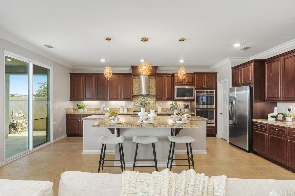 33802 Edge Lane Temecula, CA 92592 - Photo 9 of 31 a kitchen with stainless steel appliances kitchen island granite countertop a refrigerator a stove a sink and a dining table with wooden floor