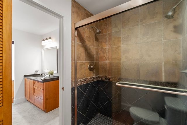 a bathroom with a granite countertop sink a mirror and shower
