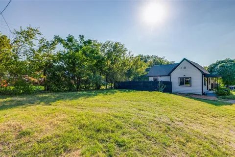 a view of yard with green space and trees in the background