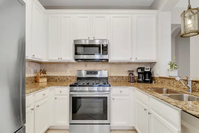 a kitchen with granite countertop white cabinets stainless steel appliances and sink