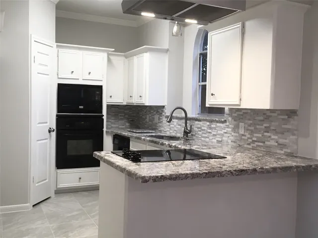 a kitchen with granite countertop a sink a stove and a window
