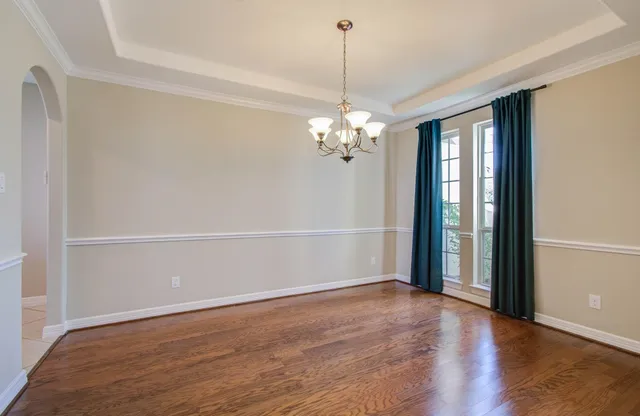 a view of a hallway with wooden floor and a kitchen