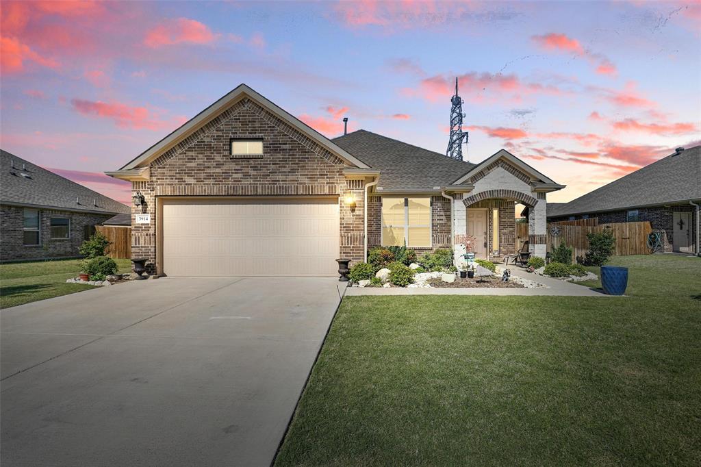 View of front of property featuring a garage, driveway, a front yard, and brick siding