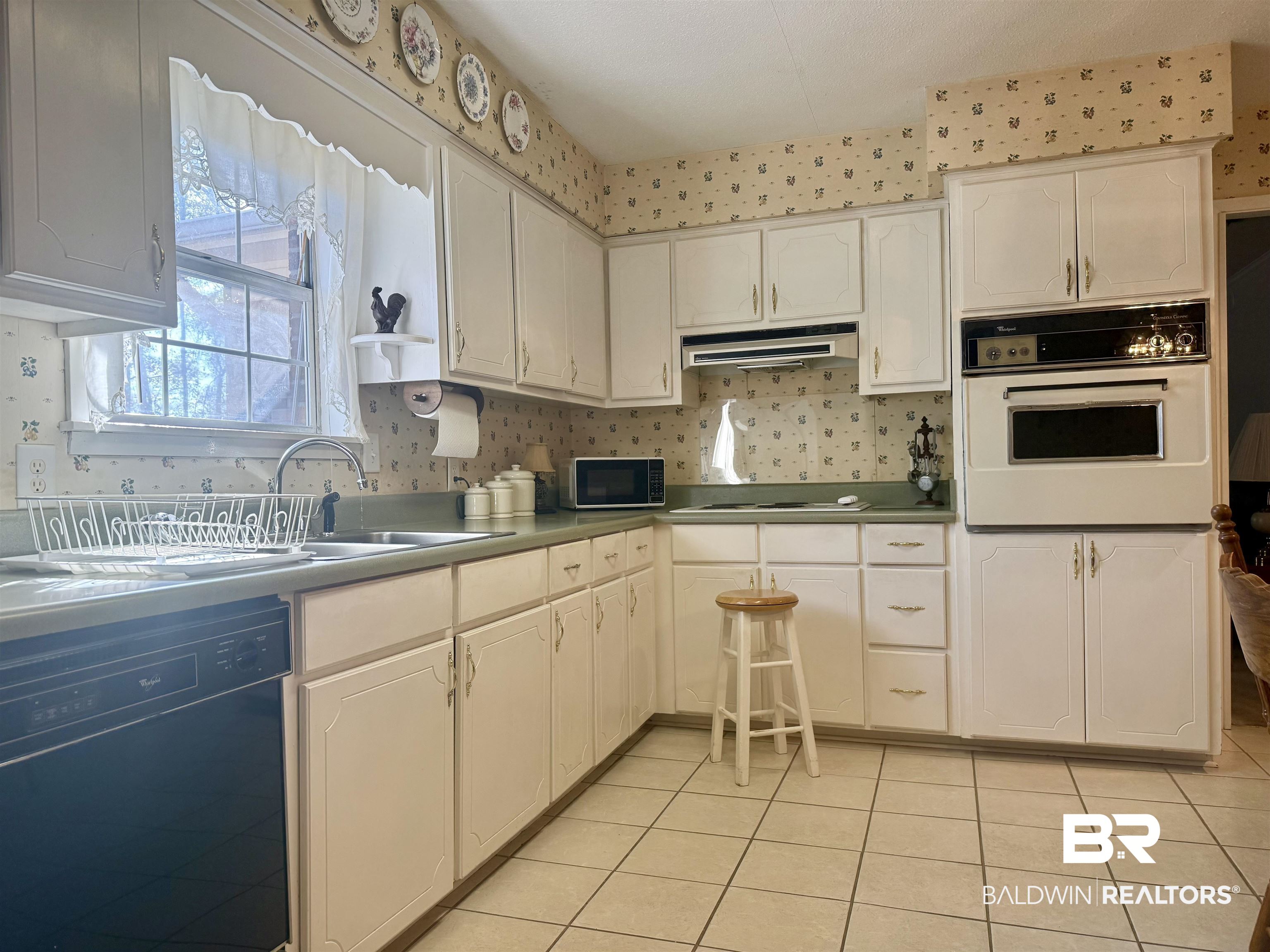 215 Young Street Brewton, AL 36426 - Photo 4 of 25 Kitchen with white oven, dishwasher, light tile patterned floors, under cabinet range hood, and white cabinetry