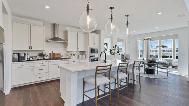 a large kitchen with cabinets a sink a stove and wooden floors