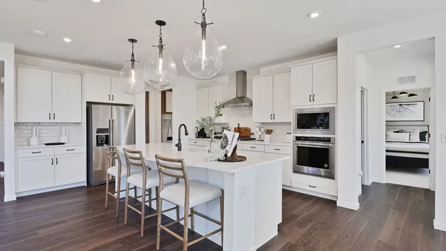 a kitchen with stainless steel appliances a stove a sink a refrigerator and chairs