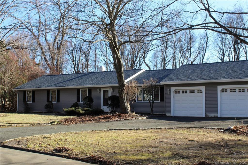 a front view of a house with a yard covered with snow and trees