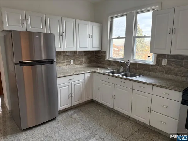 a kitchen with white cabinets white stainless steel appliances and sink