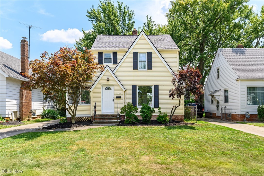 View of front of home with a front yard and a shingled roof