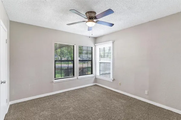 an empty room with window and ceiling fan