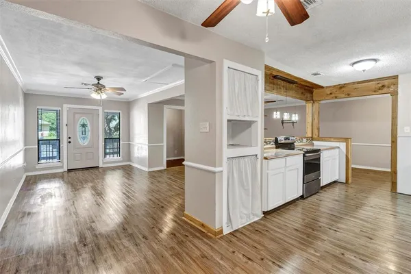 a kitchen with white cabinets and wooden floor