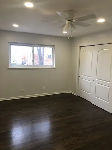 an empty room with wooden floor cabinet and windows