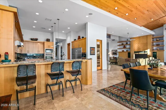 a kitchen with stainless steel appliances kitchen island granite countertop a table chairs in it and wooden floors