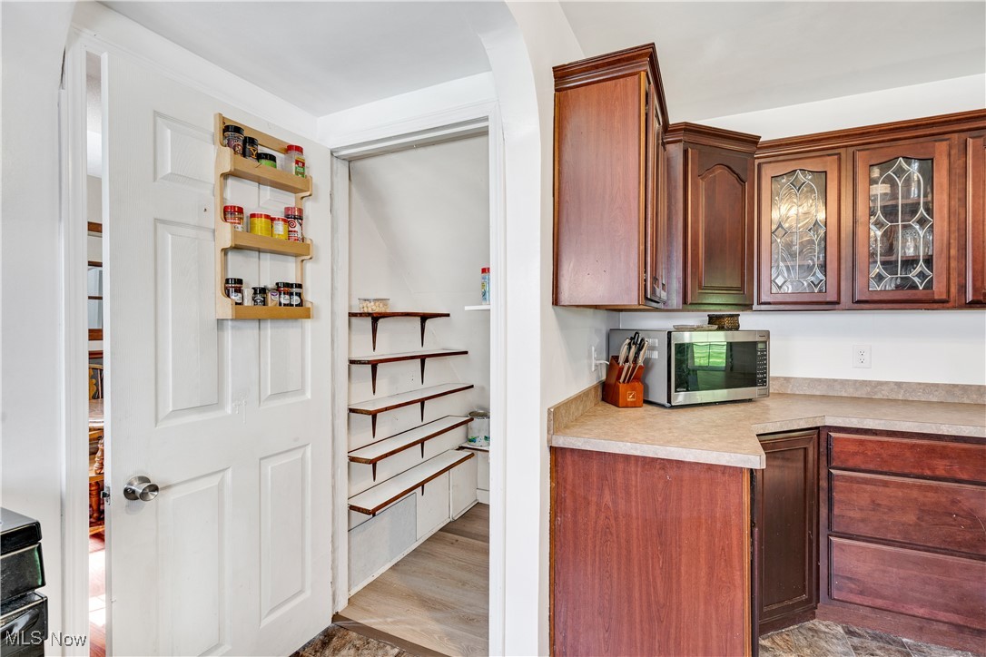 929 Johnson Plank Road Warren, OH 44481 - Photo 10 of 21 Kitchen with stainless steel microwave, light countertops, glass insert cabinets, light wood-type flooring, and arched walkways