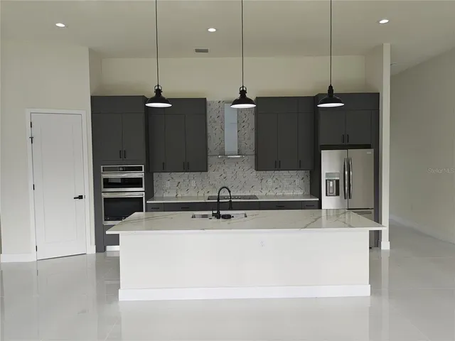 a large kitchen with kitchen island a counter top a refrigerator a sink and a stove