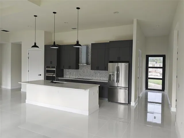 a kitchen with stainless steel appliances kitchen island granite countertop a refrigerator a oven and a stove with granite countertops