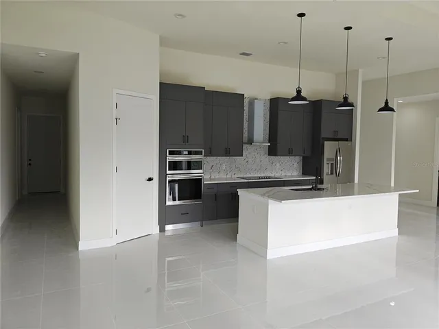 a large kitchen with kitchen island a counter top a stove a sink and a refrigerator