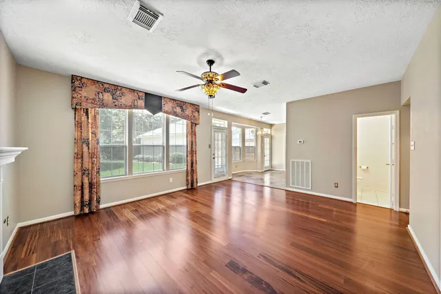a view of an empty room with a window and wooden floor