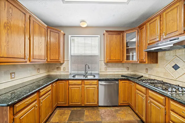a kitchen with stainless steel appliances granite countertop a sink stove and cabinets