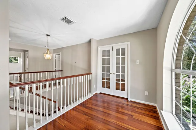 a view of a hallway with wooden floor and windows