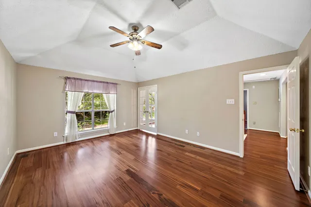 a view of an empty room with wooden floor and a window