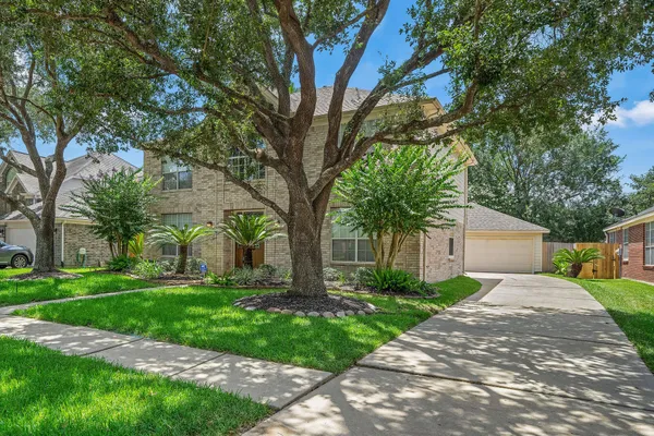a front view of a house with a yard and a tree