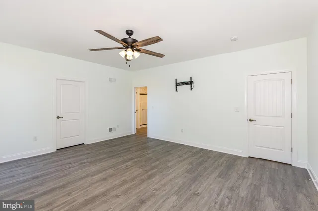 a view of a big room with wooden floor closet and ceiling fan