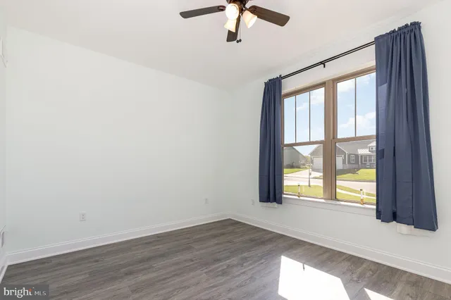 an empty room with a window and ceiling fan
