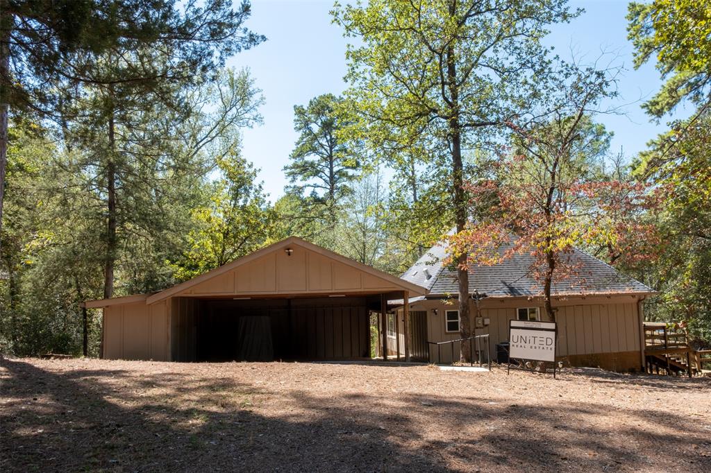 167 Blue Water Point Holly Lake Ranch, TX 75765 - Photo 26 of 27 Wood-sided exterior structure with a covered parking area, a separate wood-sided building featuring a gable roof, and an exterior wood staircase