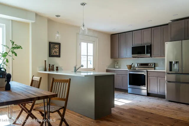 a kitchen with stainless steel appliances kitchen island granite countertop a stove a sink a microwave a dining table and chairs