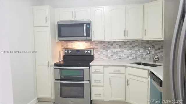 a kitchen with white cabinets and stainless steel appliances