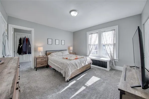 a bedroom with a bed and a flat tv screen on the dresser