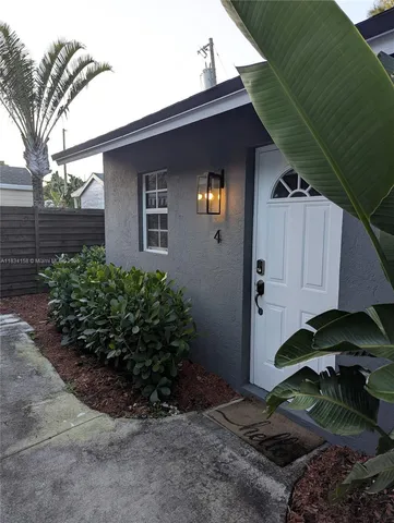 a backyard of a house with potted plants and large tree
