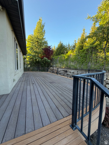 4536 North 475 East Provo, UT 84604 - Photo 53 of 65 Spacious composite deck featuring a curving edge, black metal railings, and a backdrop of mature trees