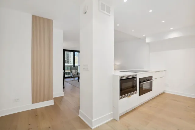 a view of a kitchen with a sink and dishwasher a stove top oven with wooden floor