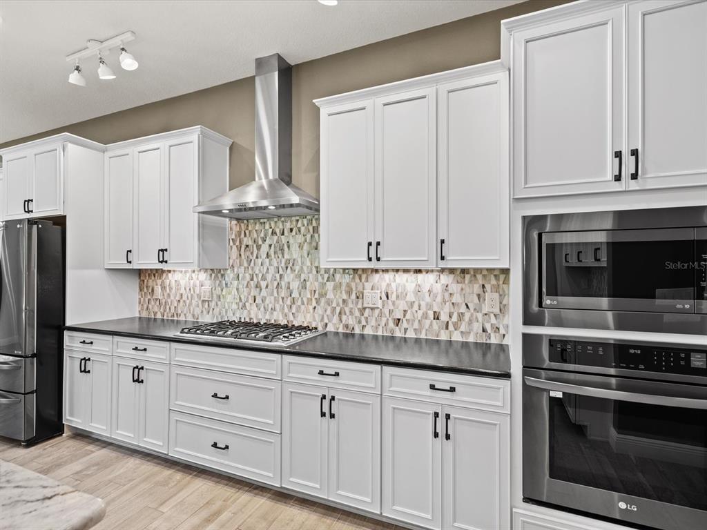 11981 Robina Road Weeki Wachee, FL 34614 - Photo 13 of 93 a kitchen with granite countertop white cabinets and stainless steel appliances