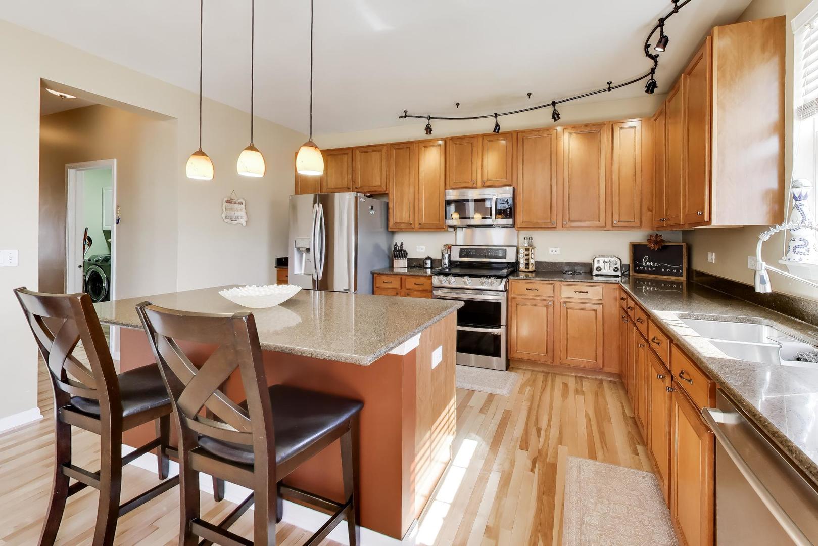 343 Copper Springs Lane Elgin, IL 60124 - Photo 6 of 50 a kitchen with stainless steel appliances kitchen island granite countertop a sink a stove and a wooden cabinets