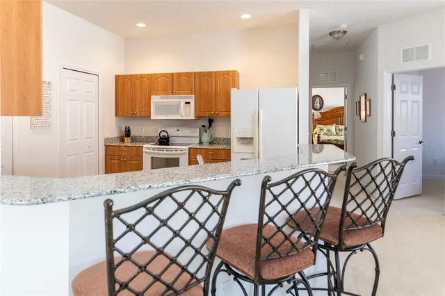 a kitchen with stainless steel appliances granite countertop a table chairs and a refrigerator