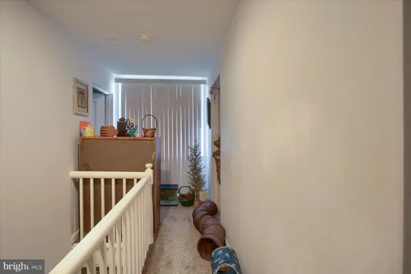 a view of a hallway to a livingroom with wooden floor and windows