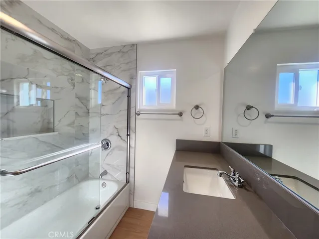 a bathroom with a granite countertop sink a toilet a mirror and bathtub
