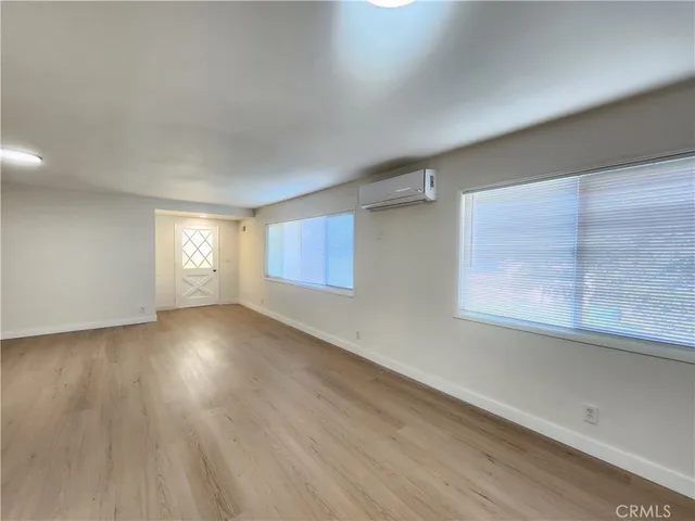 a view of empty room with window and wooden floor